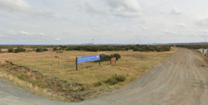 Liawenee area showcasing a dirt road leading to a signpost, with expansive fields and a cloudy sky in the background .google map
