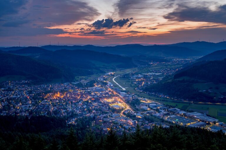 Scenic view of a city with streetlights and mountainous background at sunset, showcasing Battery Point