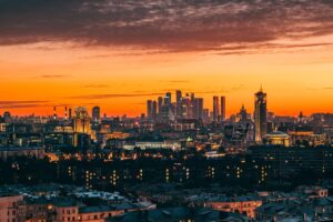 Stunning sunset view over a modern city skyline with glowing lights and a warm orange sky, including Battery Point