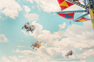 A group of people enjoying a thrilling swing ride at an amusement park with a vibrant sky in the background