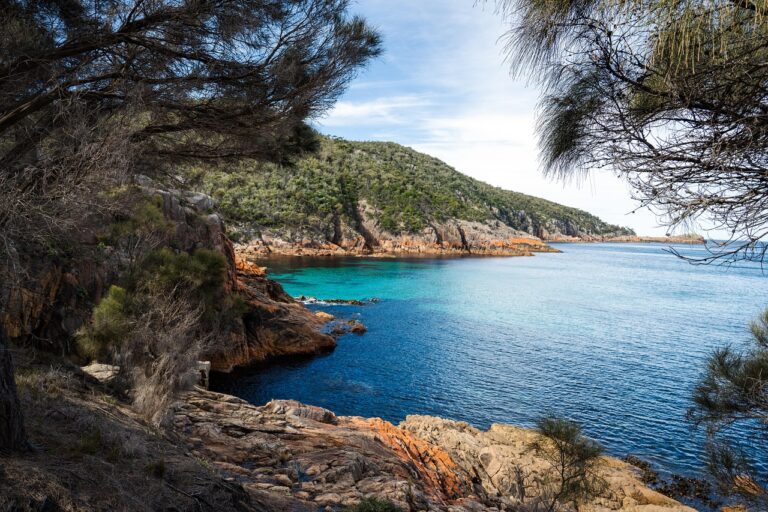 Stunning view of Freycinet Peninsula coastline with clear turquoise waters and rocky terrain surrounded by lush greenery