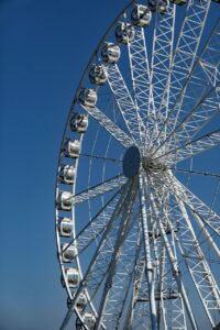 Close-up of a Ferris wheel against a bright blue sky, showcasing the cabins and the intricate structure