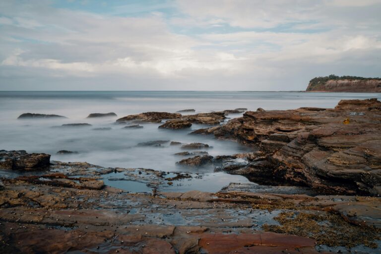 Bay of Fires coastline with smooth rocks and calm waters under a partly cloudy sky